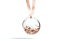 Round glass ornament filled with rose gold glitter and metallic confetti suspended on pink satin ribbon against white background.