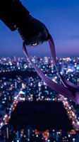 Silhouetted hand holding purple ribbon against twilight cityscape with bokeh lights below, symbolizing awareness, support, and urban connection for campaigns and charitable causes.