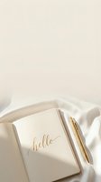 Elegant cream notebook with gold hello lettering and golden pen on soft white silk fabric, minimal aesthetic for lifestyle blogs and social media.