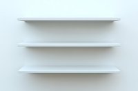Empty white floating shelves mounted on light wall, minimalist modern interior design element for displaying decor and organizing space.