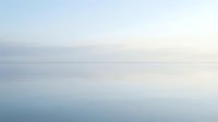 Serene calm water surface with soft horizon line under overcast sky, suitable for backgrounds and wellness concepts.
