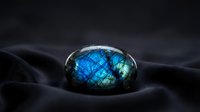 Stunning labradorite gemstone with brilliant blue flash iridescence resting on dark silk fabric creating luxurious jewelry display for precious stone collection.
