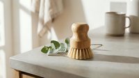 Wooden dish brush with natural bristles on kitchen counter with eucalyptus branch, eco-friendly cleaning tool for sustainable home care and zero waste lifestyle.