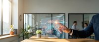 Businessman touching digital network interface with glowing connections and data visualization in modern office conference room with colleagues collaborating in background.