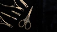 Luxury gold manicure set with scissors, nail clippers, and cuticle tools arranged on dark velvet background for beauty and grooming concepts.
