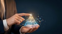 Professional businessman holding glowing holographic pyramid with digital particles floating above palm in dark blue background for technology presentations.
