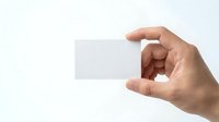 Hand holding blank white business card mockup on clean background for branding and corporate identity design projects.