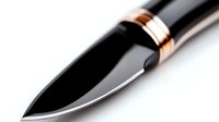 Sharp black hunting knife with copper and silver metal accents on white background, macro photography showing blade detail and craftsmanship.