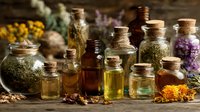 Collection of glass bottles filled with herbal oils, tinctures and dried medicinal plants on rustic wooden surface for natural wellness and aromatherapy treatments.