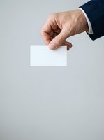Mature male hand in dark business suit holding blank white card against neutral background for corporate branding and marketing use.
