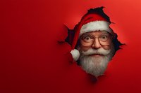 Santa Claus face with glasses and white beard peering through torn red paper hole, creating playful holiday breakthrough effect against bright red background.