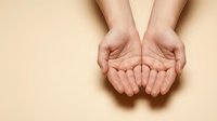 Open cupped hands gesture on beige background showing palms up in receiving position for charity, giving, support and help concepts.