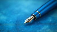 Elegant blue fountain pen with gold nib on textured blue background, symbolizing luxury writing and professional communication.