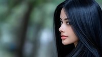 Young Asian woman with long black silky hair and red lips looking away thoughtfully against soft blurred green background, profile view portrait in natural lighting.