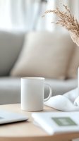 White ceramic mug on wooden table with pampas grass decoration and laptop in bright minimalist interior setting, soft beige and gray color palette.