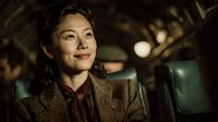 Young Asian businesswoman in vintage train car looking thoughtfully out window during evening journey with warm atmospheric lighting for travel concepts.