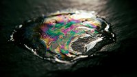 Iridescent oil slick on dark textured surface, swirling rainbow colors of pink, green, and blue in liquid puddle, macro shot.