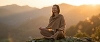 Young Asian woman meditating in lotus position on mountain rock during golden hour sunrise, peaceful mindfulness practice in nature for wellness and spirituality.