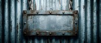 Rusty metal nameplate with rivets mounted on weathered corrugated steel wall surface creating industrial vintage background for signage applications.