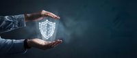 Businessman hands protecting glowing shield icon representing cybersecurity, data protection and business insurance concepts on dark background.