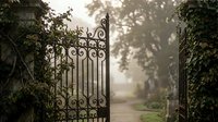 Ornate wrought iron gate with decorative scrollwork opens to misty garden path surrounded by lush greenery and mature trees in soft morning light.