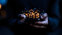 Glowing miniature houses held in cupped hands against dark background, creating magical atmosphere with bokeh lights. Concept of real estate dreams and property ownership.