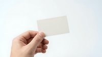 Hand holding blank white business card mockup on light background for branding and corporate identity design projects.