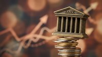 Golden bank building model on stack of coins with warm bokeh background representing financial institutions and monetary savings growth.
