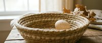 Handwoven wicker basket with fresh eggs on rustic wooden table near window, perfect for farmhouse kitchen decor and organic food storage solutions.