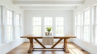 Spacious dining room with wooden trestle table, white walls, and multiple windows flooding the space with natural light for interior design projects.
