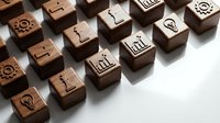 Wooden business icon stamps with gears, lightbulbs, charts and arrows arranged on white surface for corporate branding and office documentation needs.