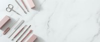 Pink and white cosmetic tools and accessories arranged on marble surface for beauty routine and makeup application.