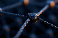 Macro shot of rope knot intersection against dark background, highlighting textured pattern and craftsmanship. Dramatic lighting creates depth and shadows.