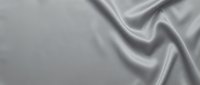 Luxurious silver silk fabric with elegant flowing waves and smooth texture creating sophisticated drapery for premium fashion and interior design projects.