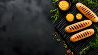 Grilled hot dogs with mustard sauce on black stone board decorated with fresh dill and spices, top view with copy space. Dark food photography.