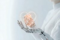 Robotic hand holding glowing orange heart shape against white background, representing artificial intelligence and emotional intelligence in technology.
