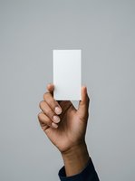 Male hand with medium skin tone holding blank white card against neutral gray background, suitable for business branding, marketing mockups, and promotional designs.