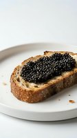 Toasted bread slice topped with black caviar served on white plate, ready for gourmet food styling, culinary presentations, restaurant menus, and fine dining concepts.