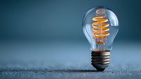 Vintage Edison light bulb with glowing spiral filament on textured surface against blue background for creative design projects and innovation concepts.