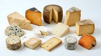 Assorted gourmet cheese varieties including aged cheddar, blue cheese, brie and gouda arranged on white background for culinary and food photography.