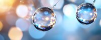 Clear water drops suspended in air against blurred blue and golden bokeh background, showcasing pure liquid spheres with light reflections and refractions.