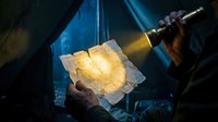 Worker holding glowing molten metal ingot under industrial lamp in factory workshop, metalworking and manufacturing process.