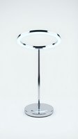Modern chrome LED ring table lamp with circular glowing halo on slim pole and round base, isolated on white background.