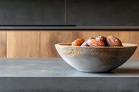 Fresh ripe dates in modern concrete bowl on gray table against wooden wall background, minimalist food styling for healthy eating concept.