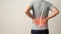 Man in gray shirt touching lower back with red pain highlight showing lumbar spine discomfort and muscle strain for healthcare and medical concepts.