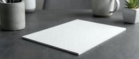 Blank white paper sheet on modern office desk with concrete planters and supplies for business presentations and creative projects.