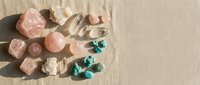 Collection of healing crystals and gemstones including rose quartz, clear quartz, and malachite arranged on neutral textured background for wellness practices.