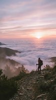 Hiker with backpack standing on mountain ridge at sunrise above sea of clouds, wearing outdoor gear and holding trekking poles for adventure and travel content.