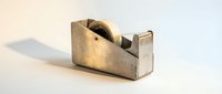 Vintage metal tape dispenser with worn brass finish and weathered patina, isolated on white background for design projects.