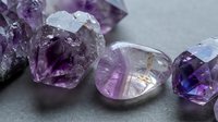 Raw amethyst crystals and polished gemstones displaying natural purple hues and crystalline formations for jewelry making and mineral collection purposes.